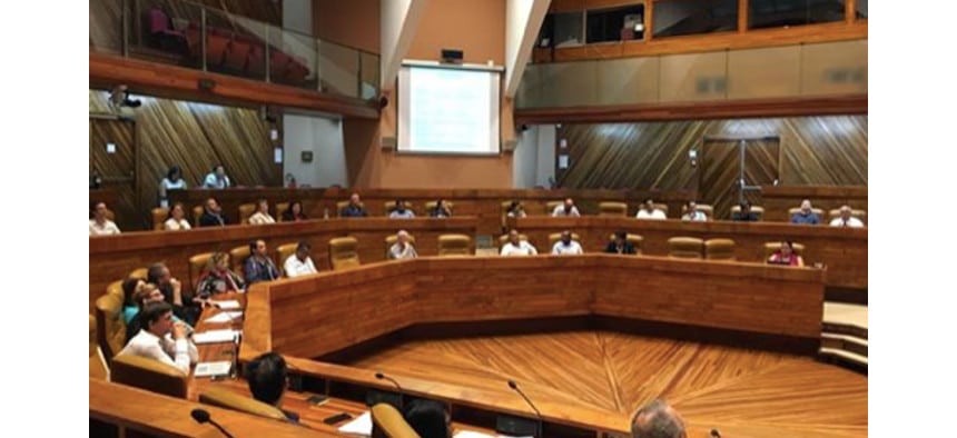 Salle de conférence avec des participants assis autour d'une table en bois.