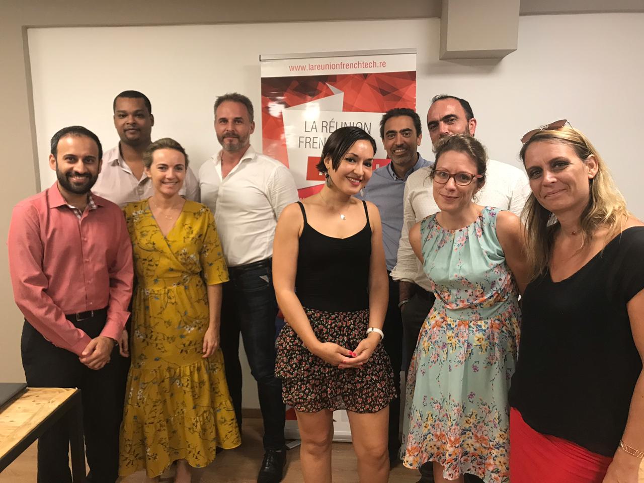 Groupe de personnes posant devant une affiche "La Réunion French Tech".