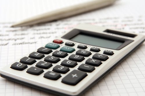 Calculatrice posée sur du papier quadrillé avec un stylo.
