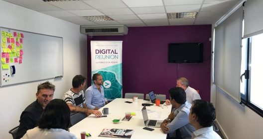 Réunion d'affaires avec sept personnes autour d'une table dans une salle de conférence.