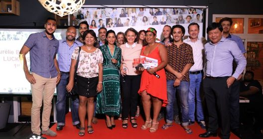 Groupe de personnes souriantes posant sur un tapis rouge lors d'un événement.