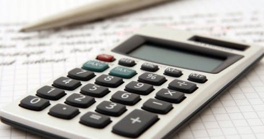 Calculatrice posée sur du papier quadrillé avec un stylo.