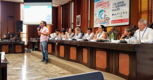 Un homme parle devant un panel lors d'une conférence sur le commerce outre-mer.