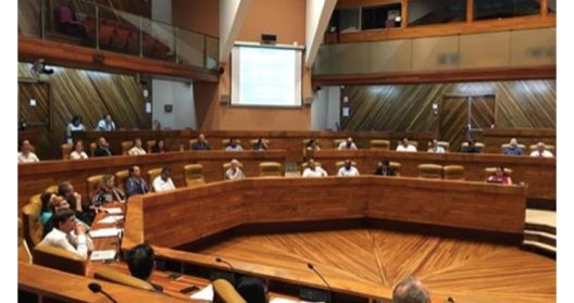 Salle de conférence avec des participants assis autour d'une table en bois.